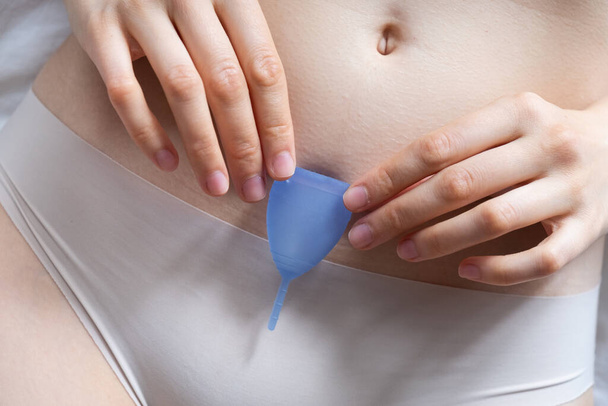 Mulher de cueca segura copo menstrual acima da barriga nua - Foto, Imagem