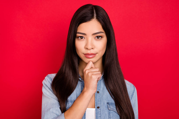 Photo of young attractive asian girl serious hand touch chin think ponder brainstorming isolated over red color background - Fotografie, Obrázek