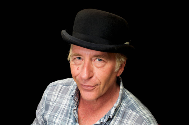 Stúdió portré szőke hajú kék szemű férfi, hogy vigyorog, elölnézet, nézi néző előtt fekete háttér, viselt kockás ing és bowler kalap. - Fotó, kép