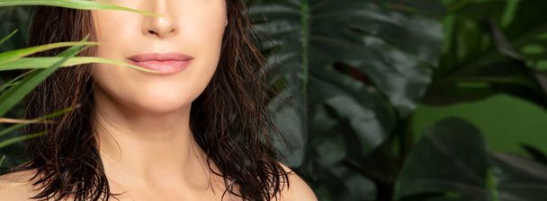 Schöne Frau mit natürlicher frischer Haut und Haaren zwischen grünen tropischen Blättern in einem Konzept von Wellness, Gesundheit und natürlicher Schönheit Hautpflege oder Wellness-Behandlungen - Foto, Bild