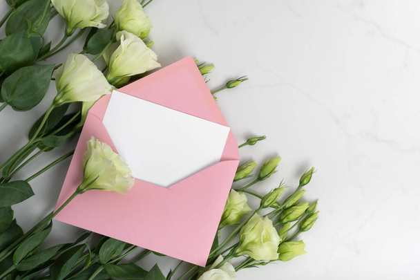 Foto verdadeira. Mockup cartão de convite quadrado envelope rosa com um eustoma flores. Vista superior com espaço de cópia, fundo de mármore cinza claro. Modelo para branding e publicidade. - Foto, Imagem