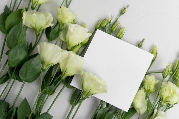 Real photo. square invitation card mockup with a eustoma flowers. Top view with copy space, light gray background. Template for branding and advertising. - Foto, Imagem