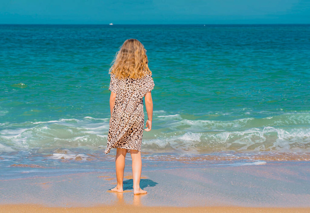 若いです美しいです女の子でベージュのドレスで実行されていますザ砂浜近くの波. - 写真・画像