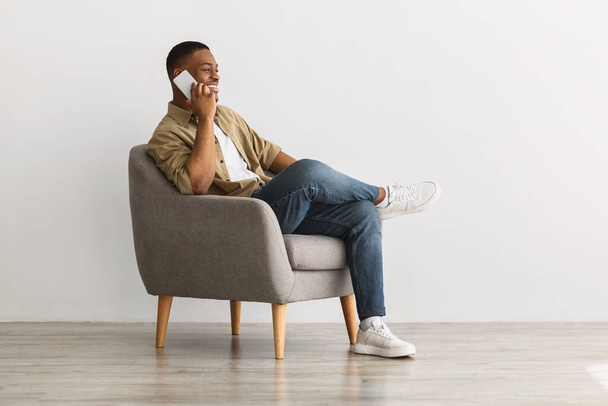 Afro-Americano Hombre Hablando Por Teléfono Sentado En Sillón Interior - Foto, imagen