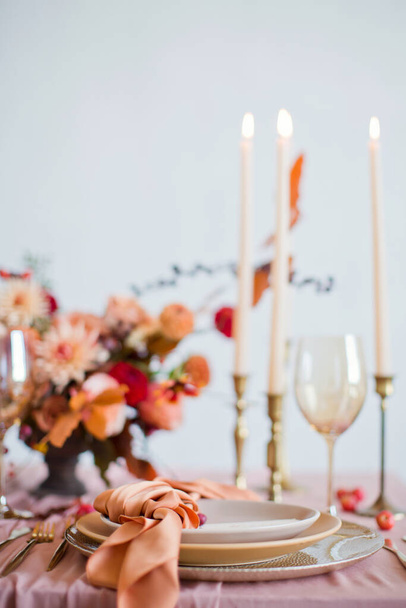 秋の花、オレンジとピンクのナプキンと燃えるキャンドルと美しいテーブルの設定。秋の結婚式のコンセプト - 写真・画像