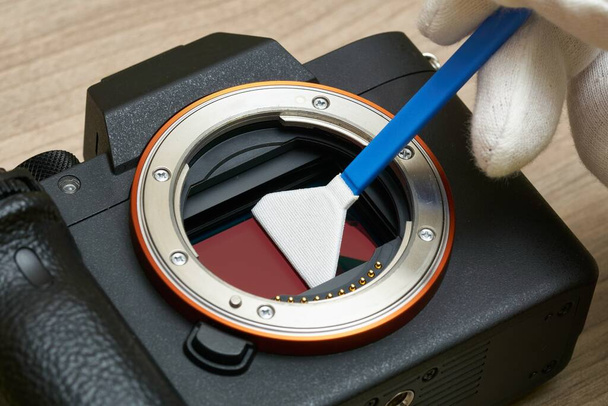 Close-up van het reinigen van een moderne digitale full-frame camerasensor met behulp van een sensoruitstrijkje - Foto, afbeelding