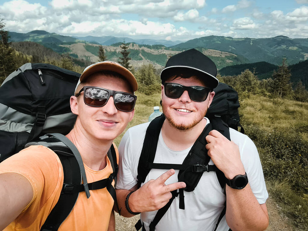 Δύο φίλοι πεζοπόροι βγάζουν selfie στην κορυφή του βουνού. έννοια καλοκαιρινή παρακολούθηση - Φωτογραφία, εικόνα