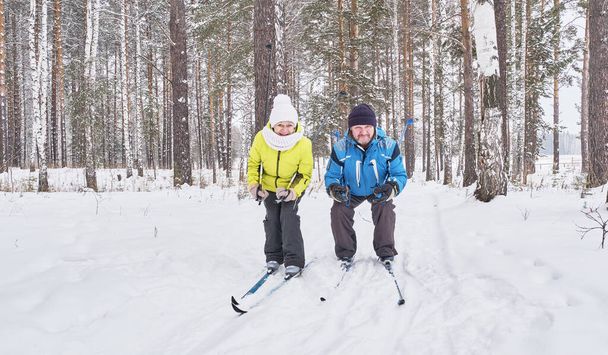 Glückliches Seniorenpaar beim Langlaufen im verschneiten Wald - Foto, Bild