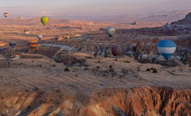 Ургуп, Каппадокія (Туреччина) - 19 березня 2021 року - панорамний вигляд повітряних кульок, що літають над дивовижними ландшафтами з феєричним комином, скелями та горами в Каппадокії. - Фото, зображення