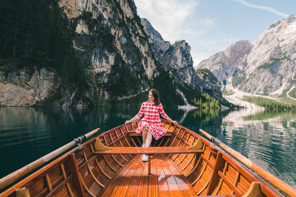 Μια γυναίκα κάθεται σε μια μεγάλη καφέ βάρκα στη λίμνη Ιάγκο ντι Μπρέις στην Ιταλία. καλοκαιρινές διακοπές - Φωτογραφία, εικόνα