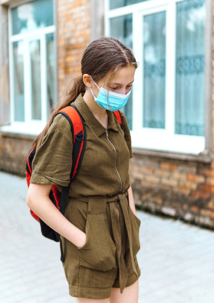 colegiala adolescente en el camino a la escuela, que utilizan mascarillas protectoras para proteger contra el virus, la infección por coronavirus, la educación y el concepto de vuelta a la escuela - Foto, imagen