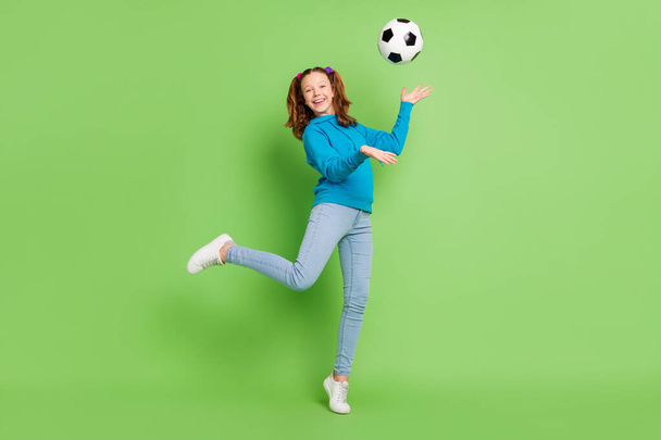 Full size photo of brunette ponytail haired little girl fly football sportive isolated on shine green color background - Fotografie, Obrázek