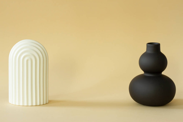 Black matte vase and plaster figure on delicate background. - Photo, Image