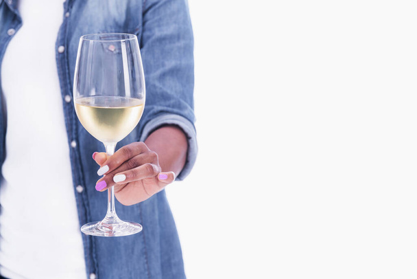 Close up of a glass of white wine being held by a female - 写真・画像