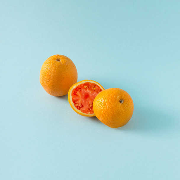 Šťavnatý pomeranč rozpůlený, v kombinaci s rajčaty. legrační koncepce.kreativní nápad na pastelové pozadí. - Fotografie, Obrázek