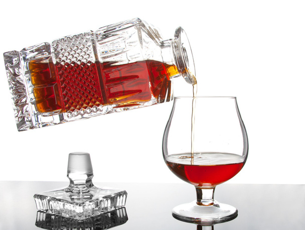 Versare il cognac dalla bottiglia in un bicchiere
 - Foto, immagini