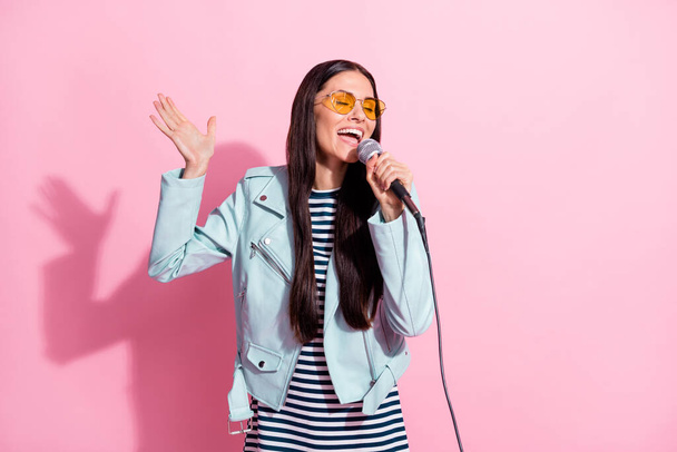 Foto von verträumt hübsch schöne Dame tragen Sonnenbrille singen Mikrofon isoliert auf pastellrosa Hintergrund - Foto, Bild