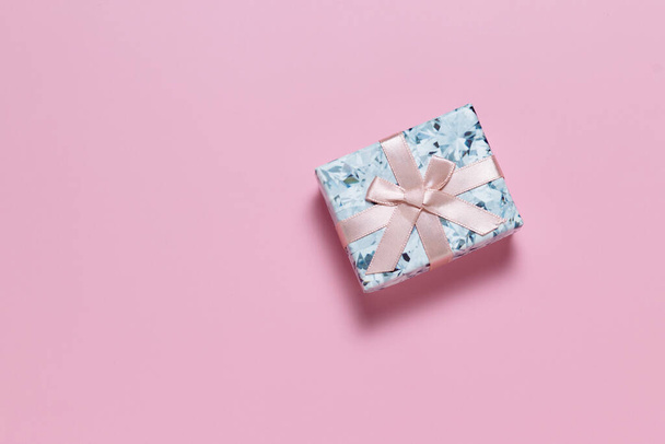 Small gift box with pink ribbon bow on pink background - Photo, image