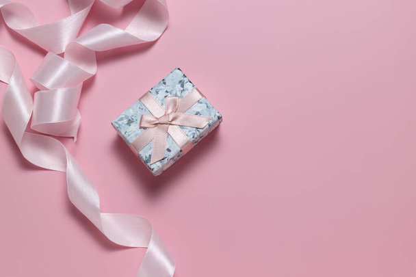 Kleine geschenkdoos met strik en roze lint voor cadeauverpakking op roze achtergrond - Foto, afbeelding