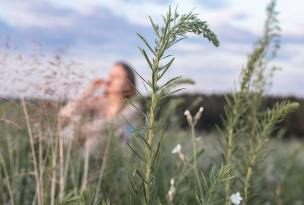 Defocused woman alone in summer field with green grass, sitting and enjoying in nature. Female in outdoor landscape - Φωτογραφία, εικόνα