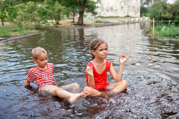 暖かい夏の雨、幸せな子供時代の後に水たまりに飛び込んで泳ぐかわいい子供たち - 写真・画像