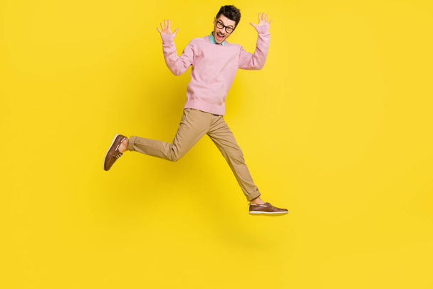 Full size photo of young cheerful man happy excited have fun jump up wave hello isolated over yellow color background - Foto, imagen