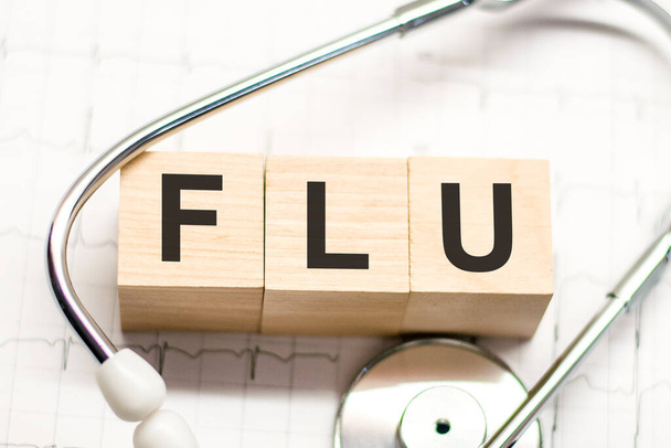 flu word written on wooden blocks and stethoscope on light background. healthcare conceptual for hospital, clinic and medical busines - Foto, Bild
