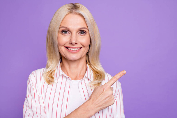 Photo of sweet shiny lady pensioner wear striped shirt pointing finger empty space isolated violet color background - Φωτογραφία, εικόνα