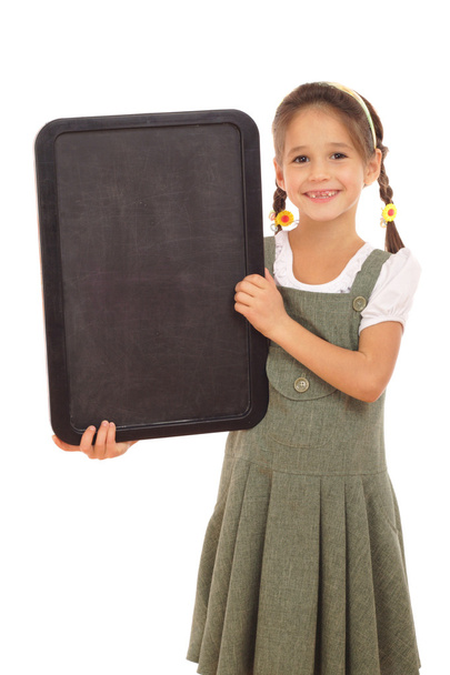 Little schoolgirl with empty vertical chalkboard, isolated on white - Photo, image