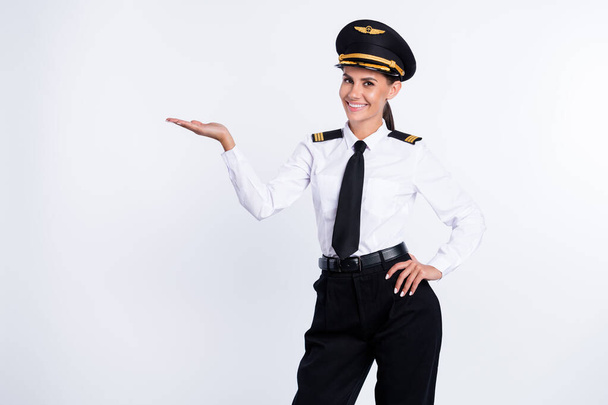 Retrato de hermosa chica piloto alegre sosteniendo en copia de la palma anuncio de espacio vacío aislado sobre fondo de color blanco - Foto, imagen