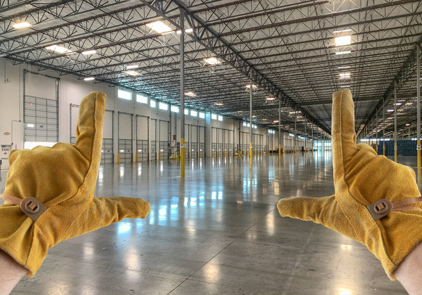 Κορνίζες χεριών με δερμάτινα γάντια σε άδεια βιομηχανική αποθήκη. - Φωτογραφία, εικόνα