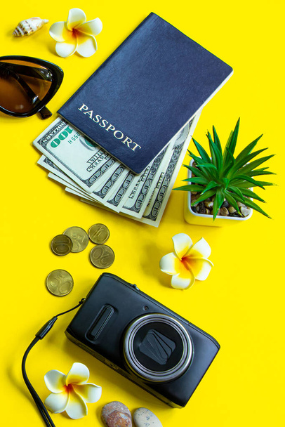 Yaz yolculuğu konsepti. Pasaport, para, güneş gözlüğü ve sarı arka planda bir kamera. Dikey biçim, metin için yer. - Fotoğraf, Görsel