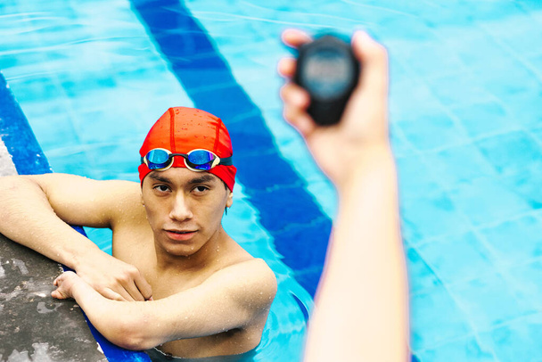 рука держит хронометр таймера с молодым человеком на заднем плане в бассейне в Мексике Латинская Америка - Фото, изображение