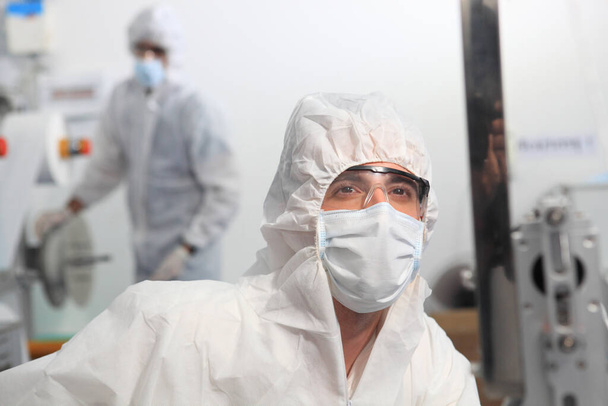 Production engineer with face mask working in factory , Qc engineer checking mask for good quality , Concept of protective action and quarantine to stop spreading of Coronavirus Disease 2019 - Photo, Image