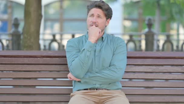 Középkorú férfi ül a szabadban, és gondolkodás  - Felvétel, videó