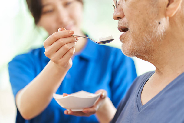 Egy gondozó, aki segíti az időseket az étkezésben. - Fotó, kép