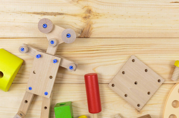 Un colorido kit de construcción de madera, un robot para niños en madera. Juego de herramientas sobre mesa de madera. Juegos y herramientas para niños en preescolar o guardería. Juguetes naturales y ecológicos. - Foto, imagen