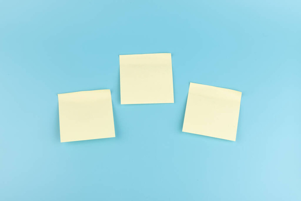 blanc carré jaune notes de papier de rappel sur fond de texture bleue.  - Photo, image