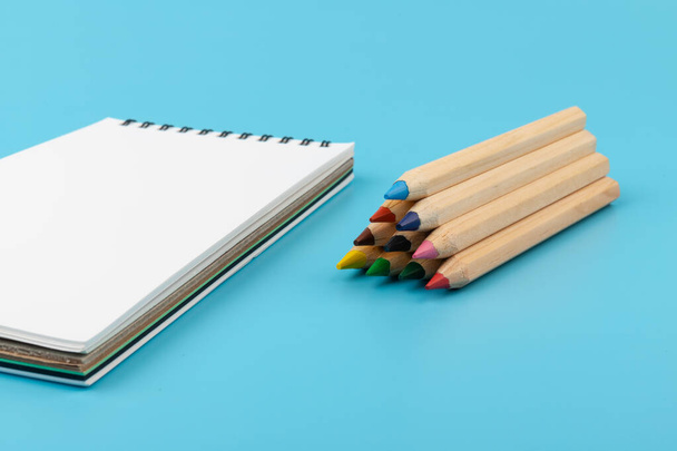 vícebarevné tužky a prázdný sešit na modrém pozadí s kopírovacím prostorem - Fotografie, Obrázek