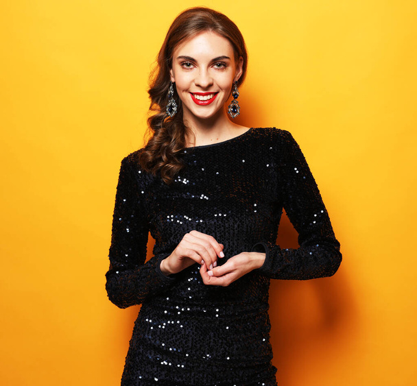 Elegant caucasian brunette woman with curly hairstyle. Charming birthday girl in sparkle dress standing in confident pose. - Фото, изображение