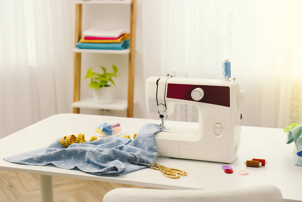 Modern sewing machine, fabric and accessories on table indoors, space for text - Fotó, kép