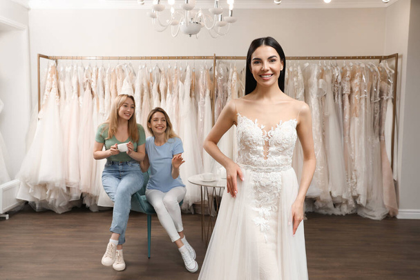 Bride with friends choosing wedding dress in boutique - Valokuva, kuva