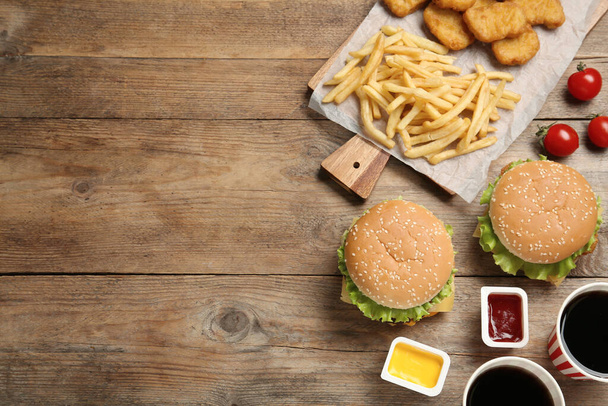 Flat lay composition with delicious fast food menu on wooden table. Space for text - 写真・画像