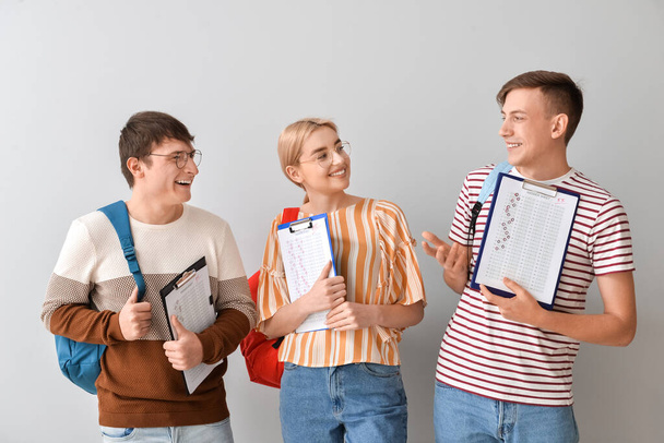 Estudiantes con hojas de respuestas para la prueba escolar sobre fondo gris - Foto, imagen