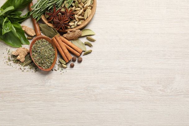 Different natural spices and herbs on light wooden table, flat lay. Space for text - Foto, Imagen