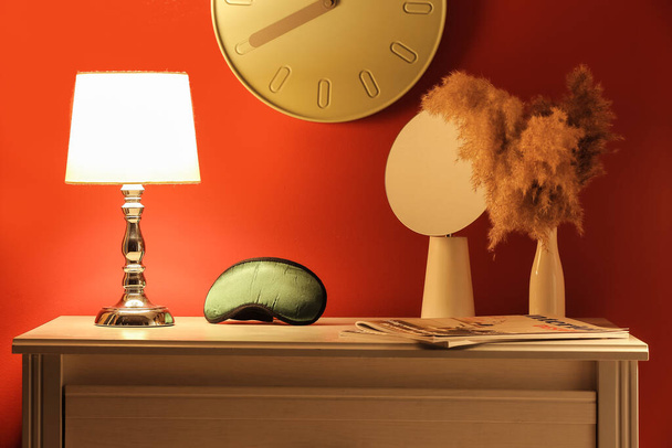 Stylish sleeping mask and lamp on shelf in room - Fotó, kép