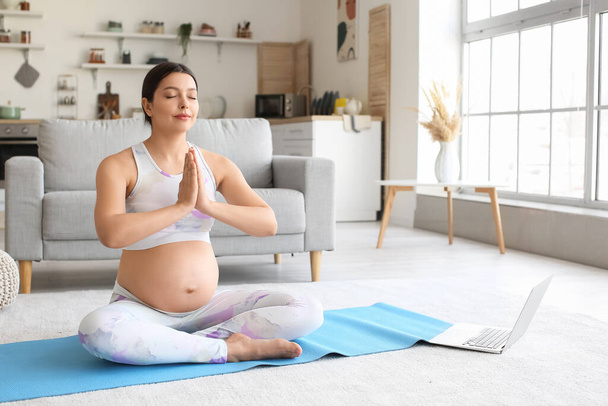 Genç hamile kadın evde yoga yapıyor. - Fotoğraf, Görsel