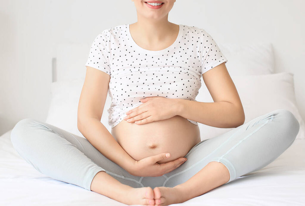 Giovane donna incinta in camera da letto - Foto, immagini