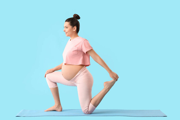 Young pregnant woman practicing yoga on color background - Foto, imagen