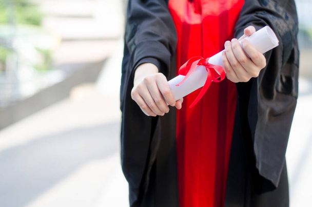 卒業証書を示す黒と赤のガウンを着ている大学生や大学生,教育的な成功の概念のために - 写真・画像